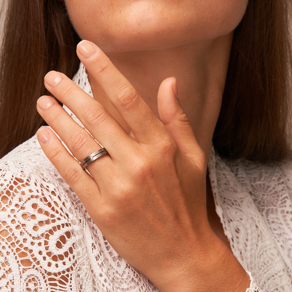 Flache Eheringe aus nickelfreiem Titan, mattiert mit Diamanten auf Hand im Gesicht