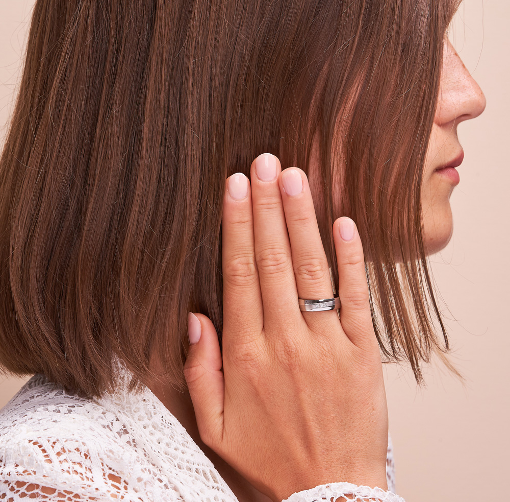 Aufnahme von Trauringen aus Stahl mit Streifen und 3 Diamanten in Vertiefung auf Hand