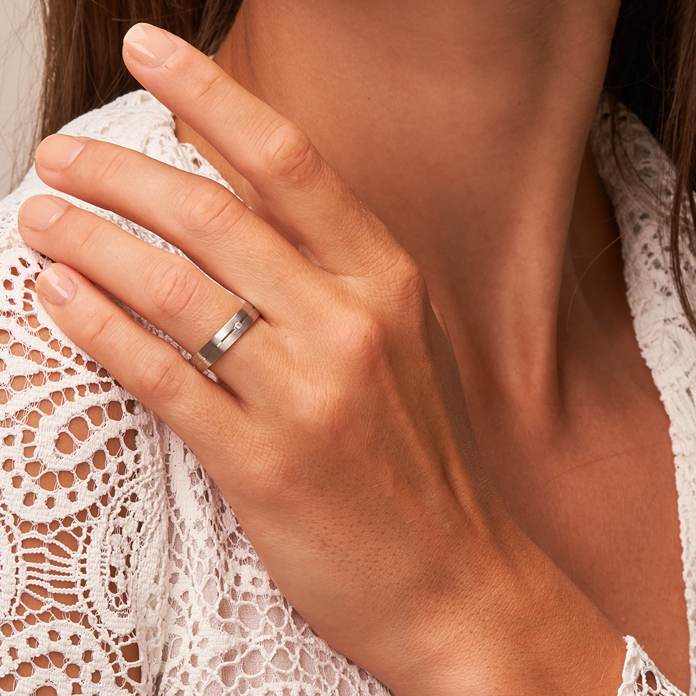 Schmale Platin Trauringe mit Längsmattierung und Diamanten auf Hand an Schulter