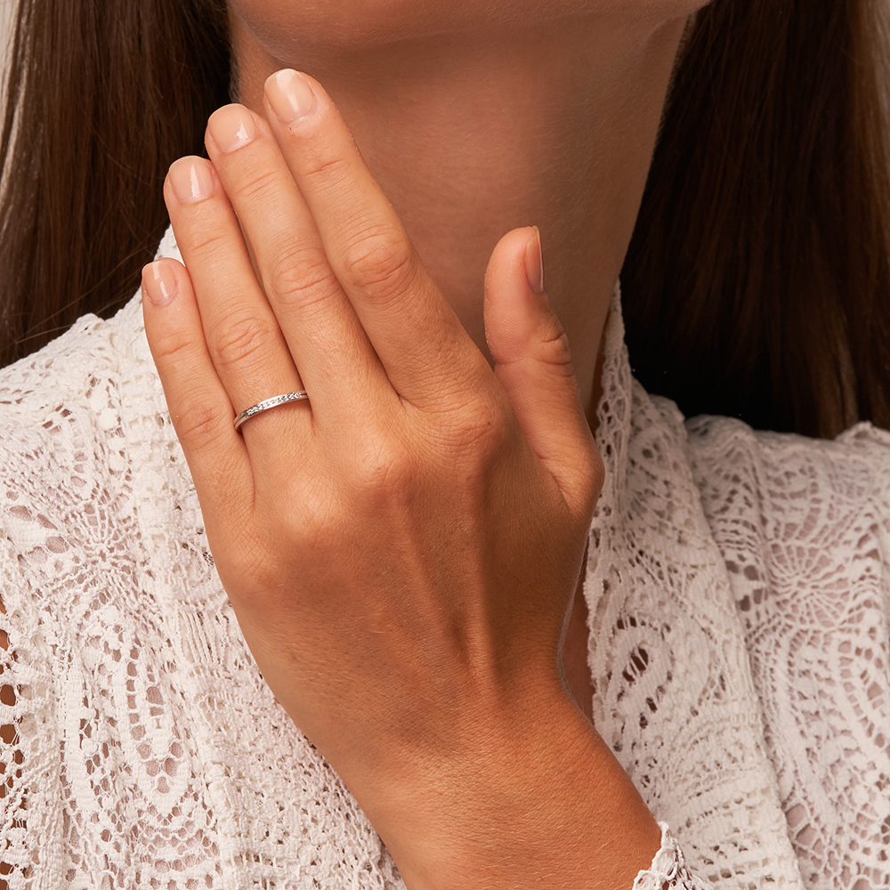 Platin Eheringe mit Eismattierung und Diamanten in Kanalfassung auf Hand am Gesicht