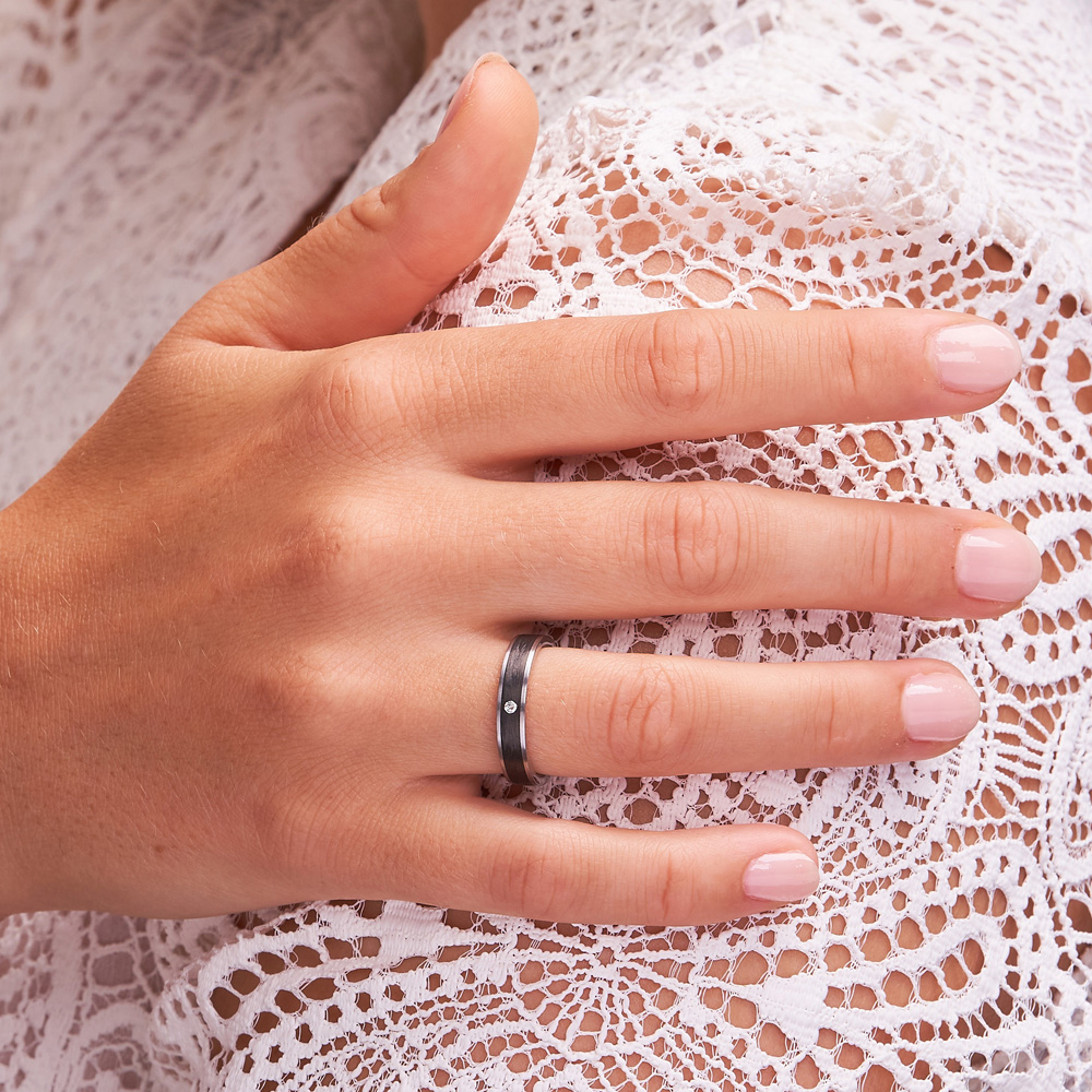 Aufnahme der Partnerringe aus mattem Carbon mit Stahl Rändern und Diamanten auf Hand