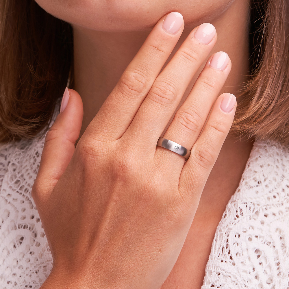 Aufnahme von matten Eheringen aus Edelstahl mit Diamanten auf Hand