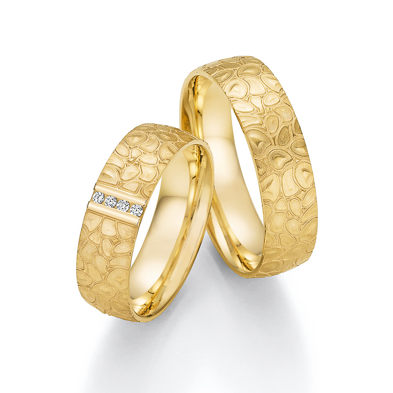 Aufnahme der Trauringe aus Gelbgold mit verspieltem Ornament und 4 Diamanten