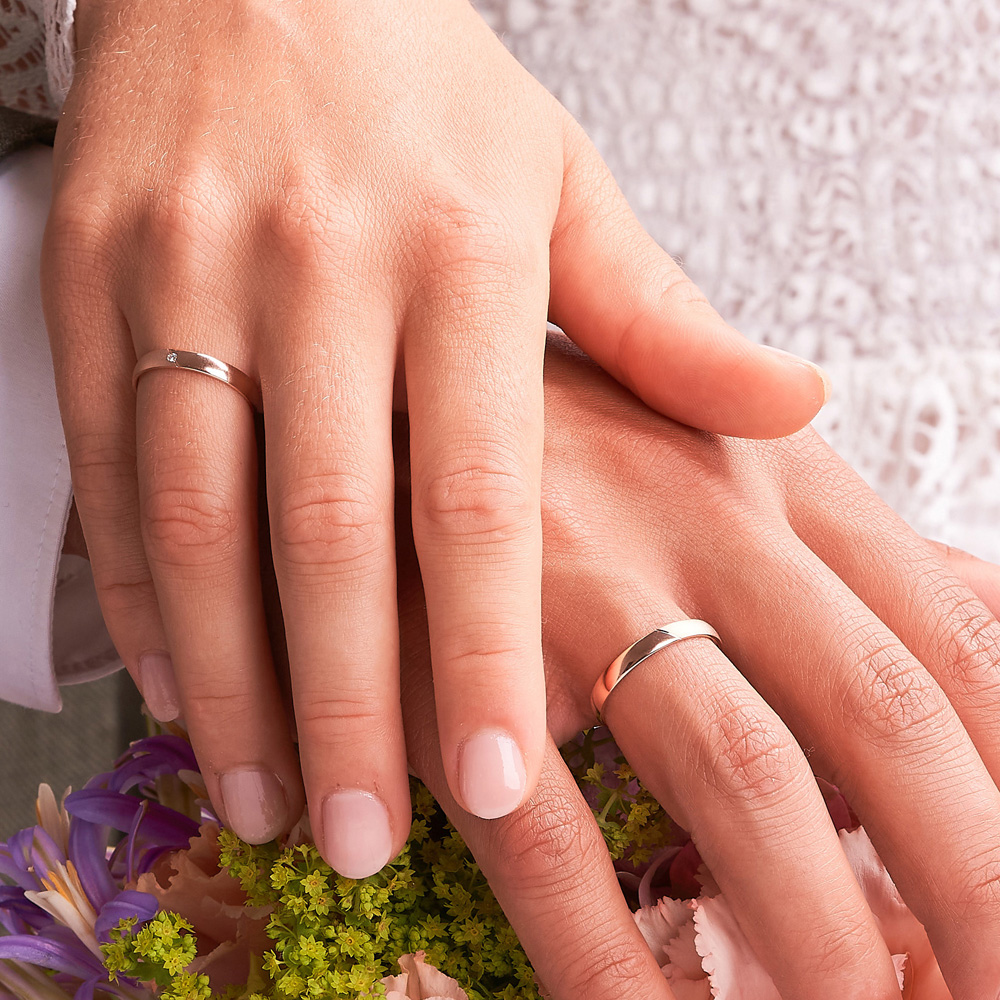 Aufnahme der Eheringe in Roségold mit glänzender und sandmattierter Flächen mit Diamanten auf Hand