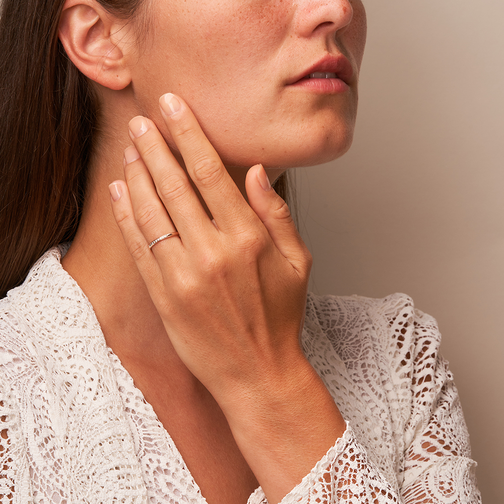 Polierter schmaler Roségold Memoire Ring mit 9 Diamanten auf Hand am Gesicht