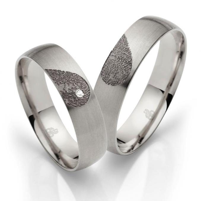 Aufnahme von Eheringen aus Palladium 500 mit Diamanten und Herzmuster mit Fingerabdruck