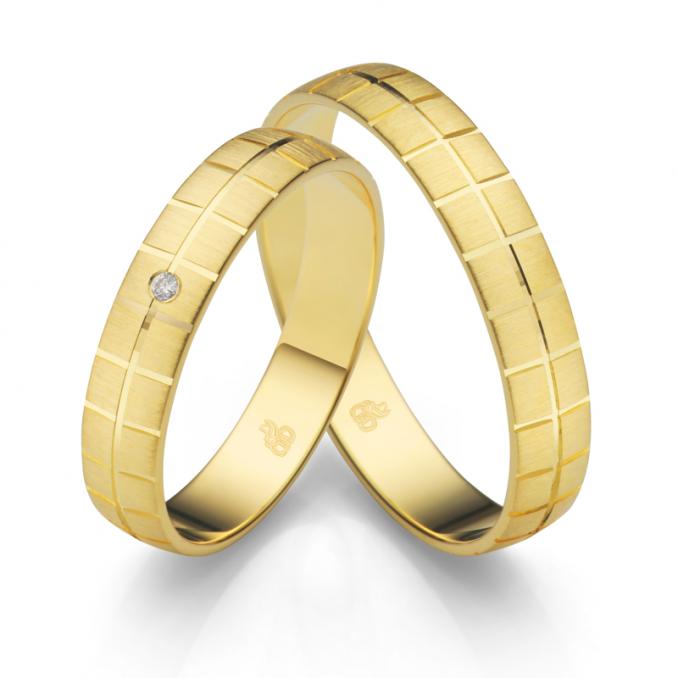 Aufnahme der Eheringe aus quermattiertem Gelbgold mit geometrischem Rillenmuster und Diamanten
