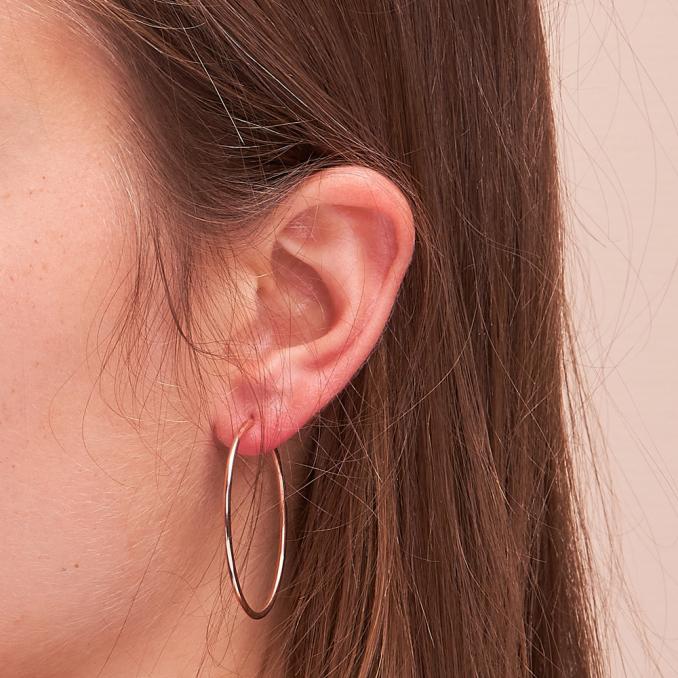 Aufnahme von Drahtcreolen aus 585er Roségold in schmalem Design auf Ohrläppchen
