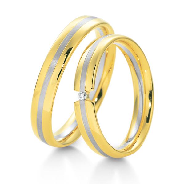 Aufnahme der Trauringe aus glattem Gelbgold mit mattem Mittelstreifen aus Weißgold und Diamant
