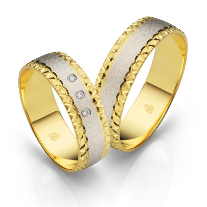 Aufnahme der Trauringe aus Gelbgold und Weißgold mit Schnörkel an Rändern und 3 Diamanten