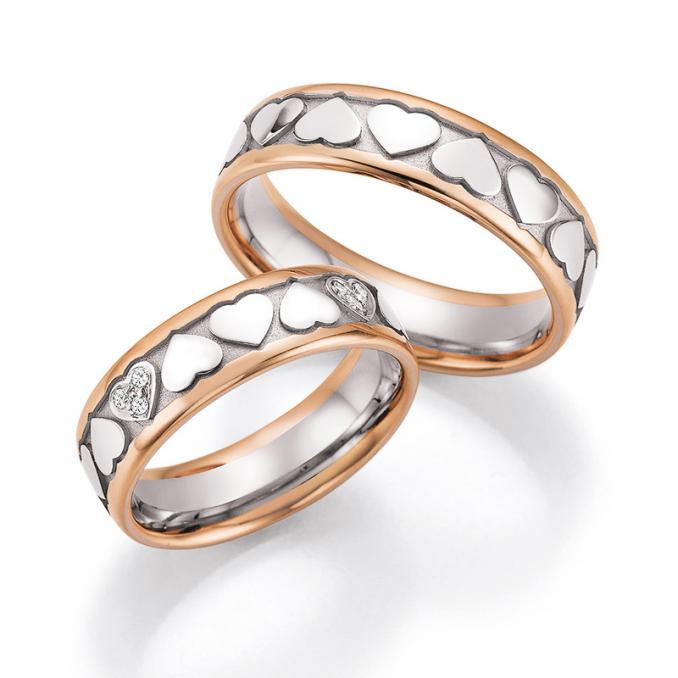 Aufnahme der Weißgold Trauringe mit Rändern aus Roségold mit Herzchendekor und 12 Diamanten