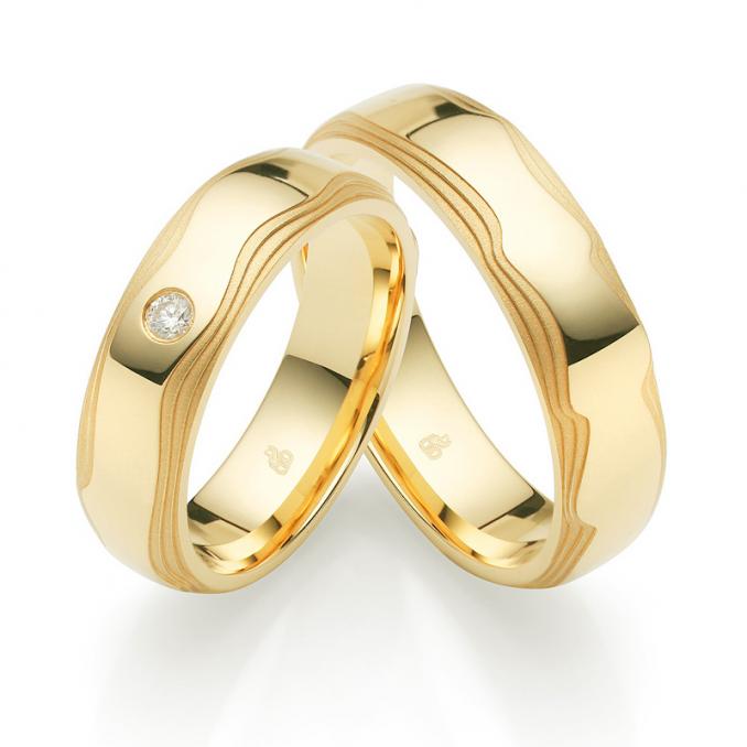 Aufnahme der Gelbgold Trauringe mit welligen Rändern in Wüsten-Design und Diamanten