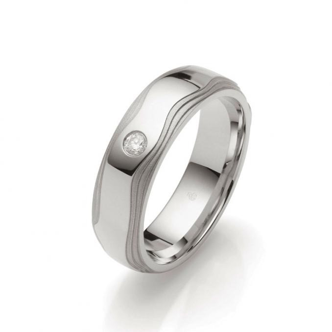 Aufnahme von stufig gestalteten Palladium 500 Trauringen mit sandmatten Rändern und Diamanten