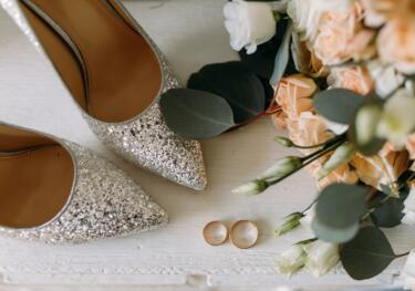 Brautschuhe, Brautstrauß, Eheringe auf Tisch