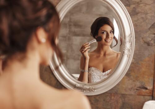 Braut schminkt sich im Spiegel