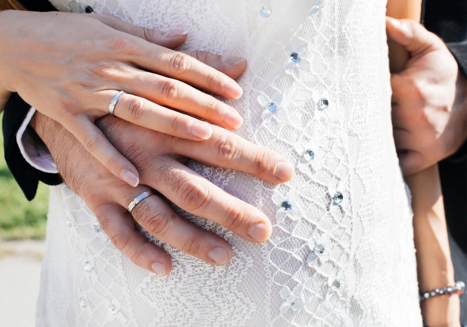 Brautpaar hält Hände am Babybauch