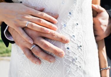 Brautpaar hält Hände am Babybauch